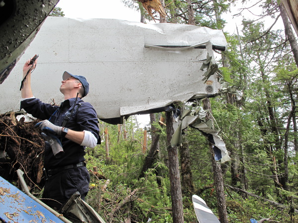 A Transportation Safety Board (TSB) investigator photographs wreckage of a Cessna 208 on Addenbroke Island, British Columbia