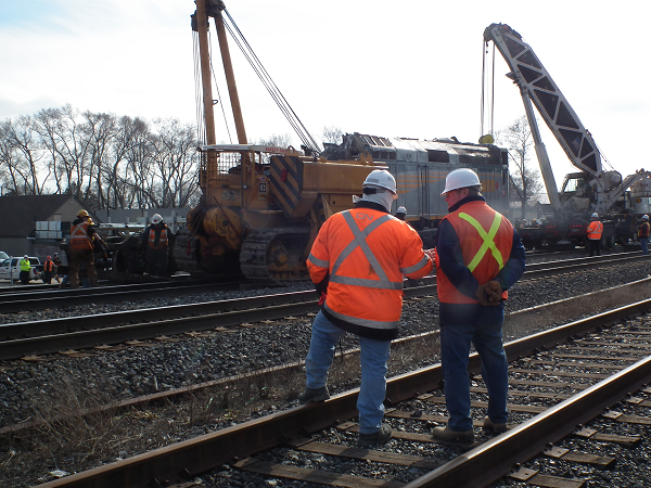A CN employee and a TSB investigator look on as VIA Rail locomotive 6444 is righted