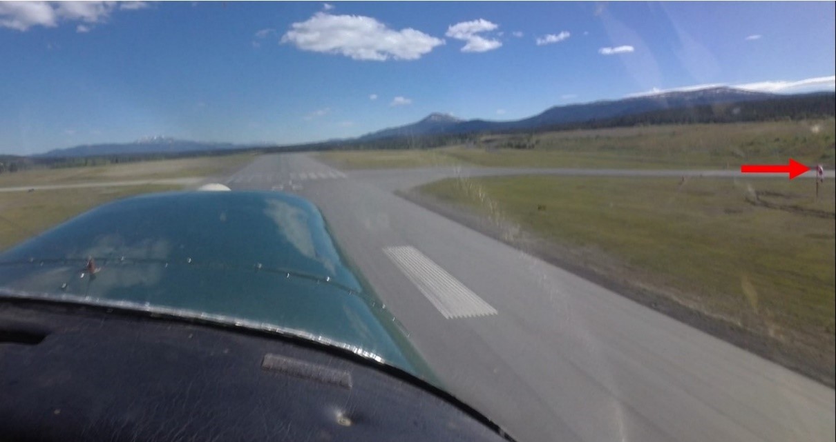 Image capture of the takeoff (at 1729:38). The red arrow points to the windsock at the far end of Runway 14R, indicating calm winds. (Source: Video recorder installed on the aircraft involved in the occurrence, with TSB annotation)
