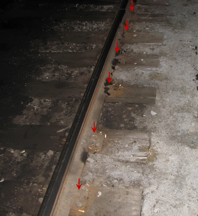 Photo of the north rail with red arrows indicating the locations of 10 inch tie plates with round spikes
