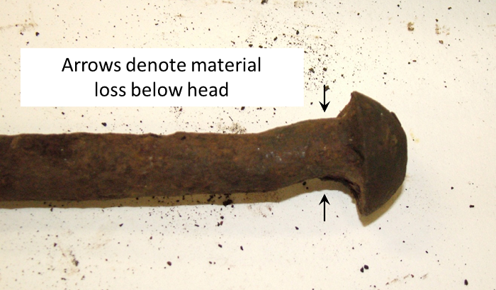 Photo showing the round track spike with arrows indicating material loss below head