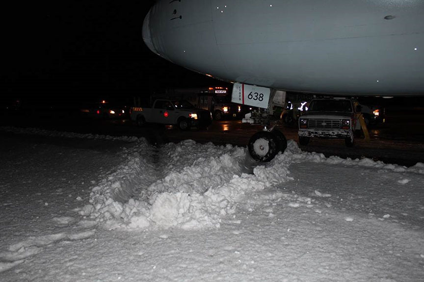 Front nose wheel in snow ridge at the edge of the runway
