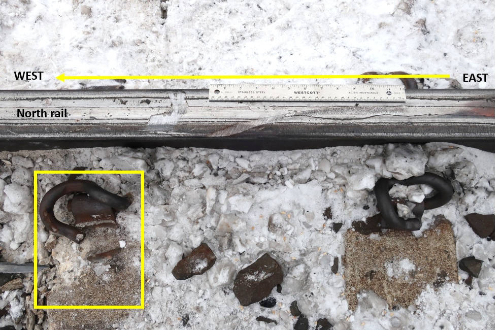 Wheel marks on the top of the north rail and the damaged gauge-side track fastener and tie (shown in the box) at Mile 166.33 (Source: TSB)