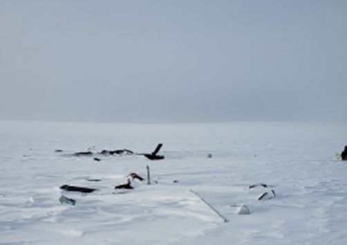 The uniformly snow-covered, featureless terrain and overcast sky at the site of an accident in Nunavut